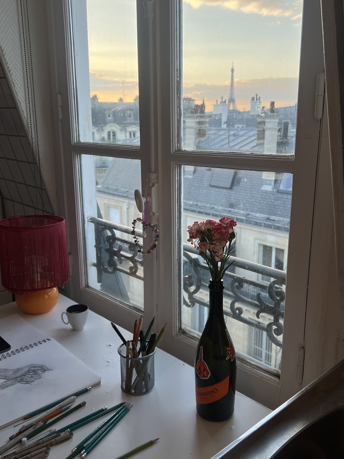 Lauren's Paris studio desk with sketchbook, pencils and a view over the rooftops